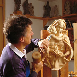 Bildhauer schnitzt Marienfigur mit Kind